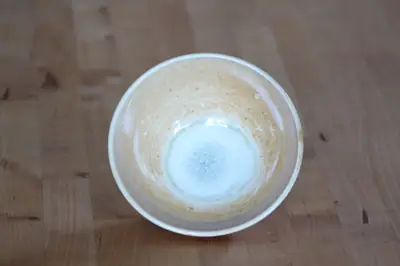 A medium bowl, glazed with shino, seen from above on a wooden table